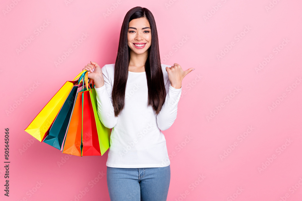 Photo of cute millennial brunette lady hold bags indicate promo wear simple cloth isolated on pink color background