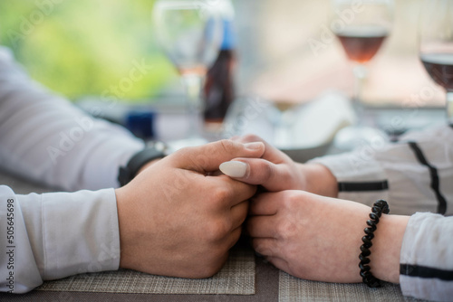 Picture of man putting engagement golden ring on woman hand. Restauraunt background.