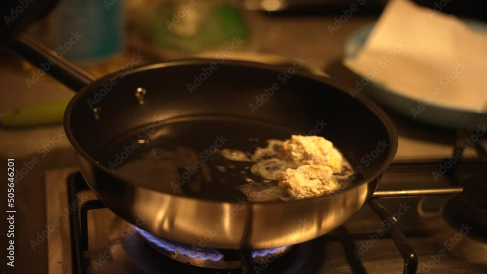 Closeup of a person's hand putting bite-sized morsels of veal brain in a frying pan full of oil Closeup of a person's hand putting bite-sized morsels of veal brain in a frying pan full of oil
