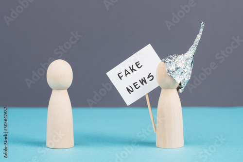 Alu hats protester talking to a person, conspiracy theories, tin foil on the head, holding a sign with fake news, conversation and communication concept photo