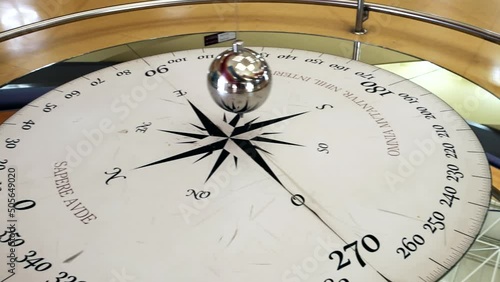 Foucault pendulum swinging on a compass rose. The text in latin 