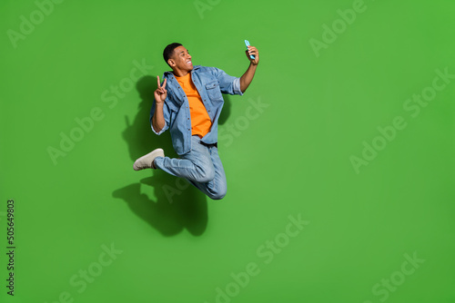 Full body profile side photo of young influencer guy take selfie show v-sign make blog post isolated on green color background