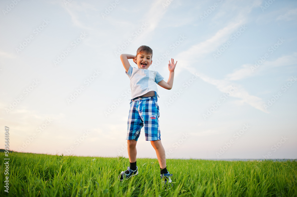Cute jumping boy in green grass field at evening. Cute jumping boy in green grass field at evening.