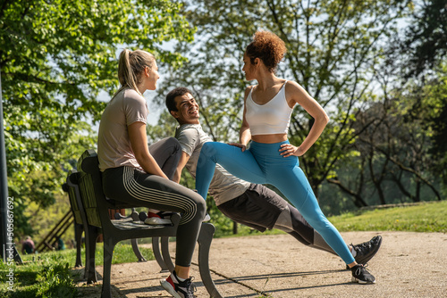 Young people workout at the park. Blonde female doing push ups and her female friends cheering her up. © BalanceFormCreative