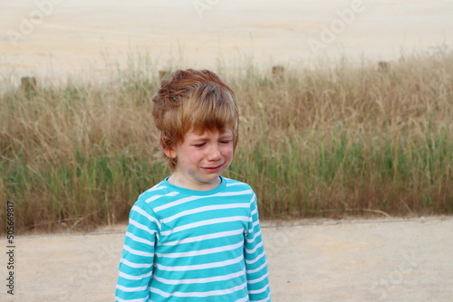 The blond boy lowered his eyes and cries. Frustrated five year old boy.