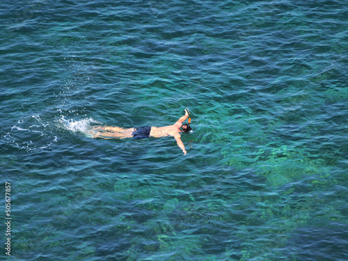 A free diver swimming in a blue  transparent sea.