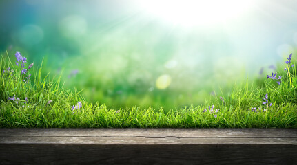 A wooden table product display with a fresh spring garden background of green grass and blurred foliage with strong sunlight.