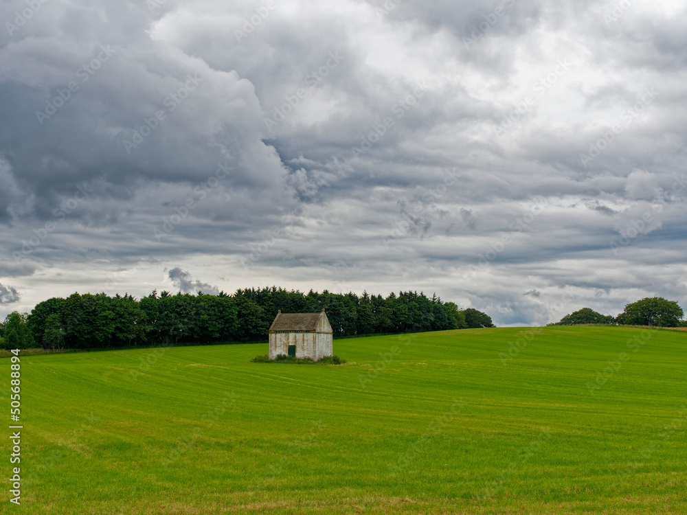 A lone white lime stained stone Doocot or Dovecot in a Field of newly sown wheat in farmland behind Montrose Beach.