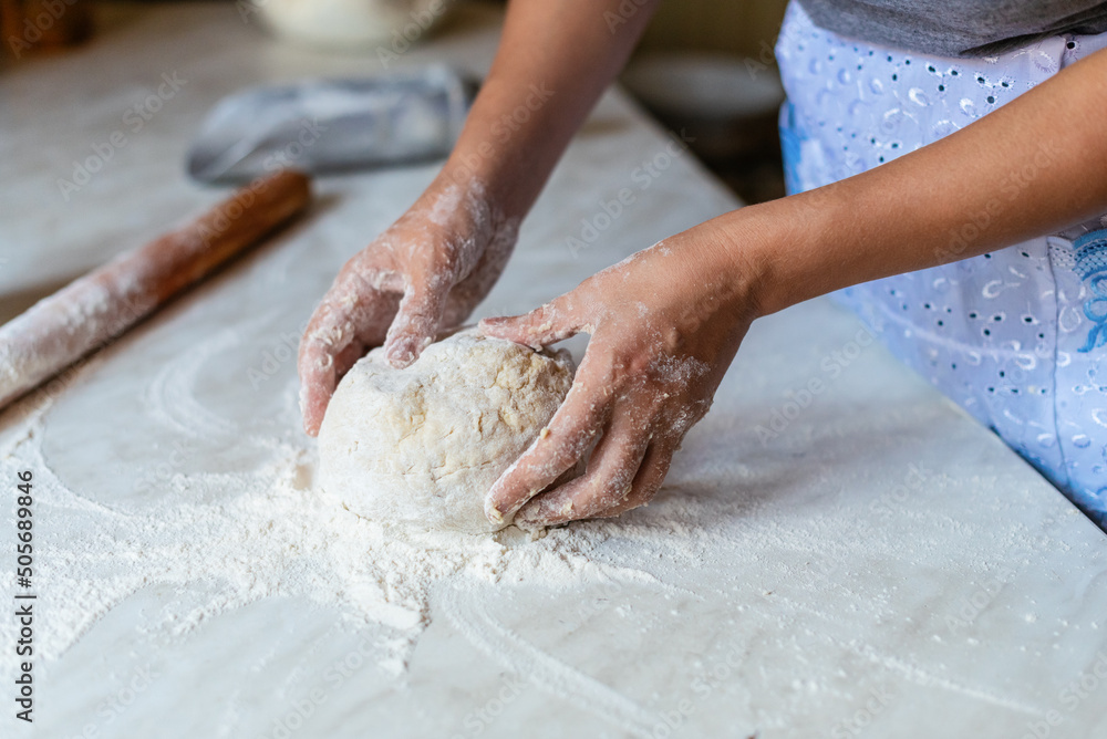 Hands of a young woman, kneading dough to make bread or pizza at home. Production of flour products. Making dough by female hands.
