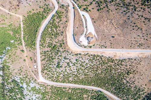 Meandering serpentine road in the mountain with small village house. Aerial view. Copter, drone view