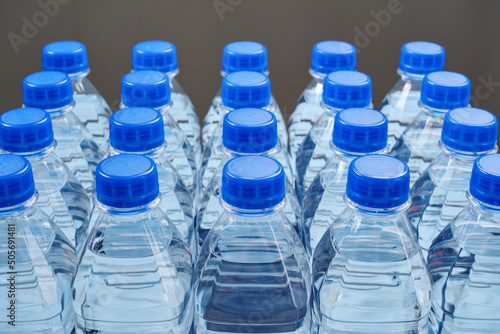 Water bottles with blue lids on a dark background. Mineral water bottles, plastic bottles. Shallow depth of field