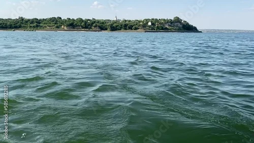 View from the water on coast of Tsimlyansk reservoir. In distance there is a steep coast, a rotunda and platinum against background of sky and sea waves. photo