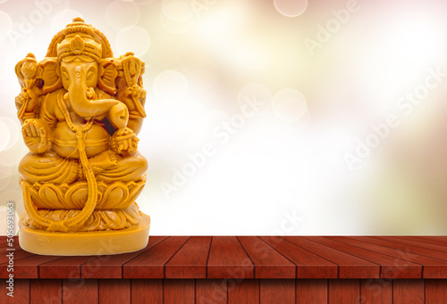 Hindu God Ganesha on a wooden table with blurred bokeh background photo