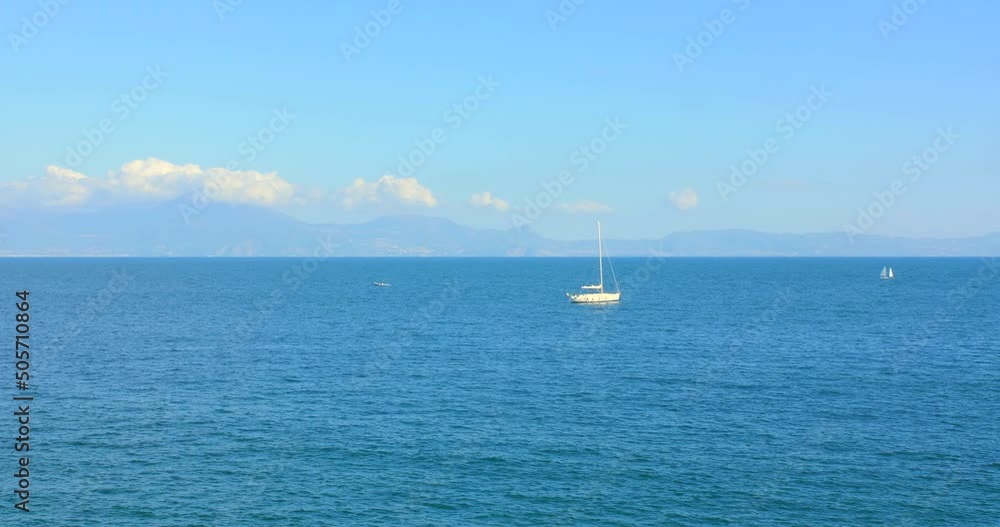Beautiful view of the Mediterranean Sea with crystal clear blue water, mountains and sailing boat filmed from Naples, Italy Beautiful view of the Mediterranean Sea with crystal clear blue water, mountains and sailing boat filmed from Naples, Italy