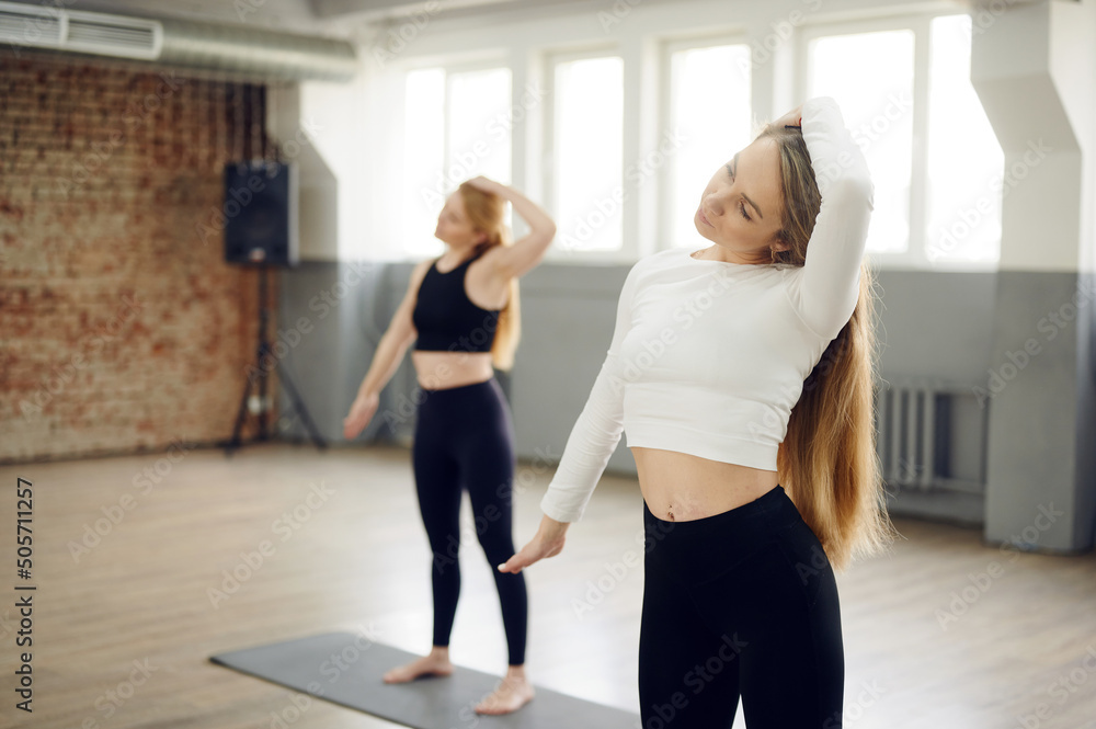 Group of people stretching at yoga class in fitness studio, woman streching body, lesson with instructor, working out Group of people stretching at yoga class in fitness studio, woman streching body, lesson with instructor, working out