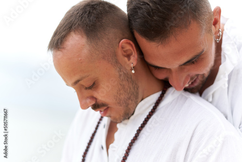 Portrait of two gay men in white clothes embracing with tender expression © DavidMorillo