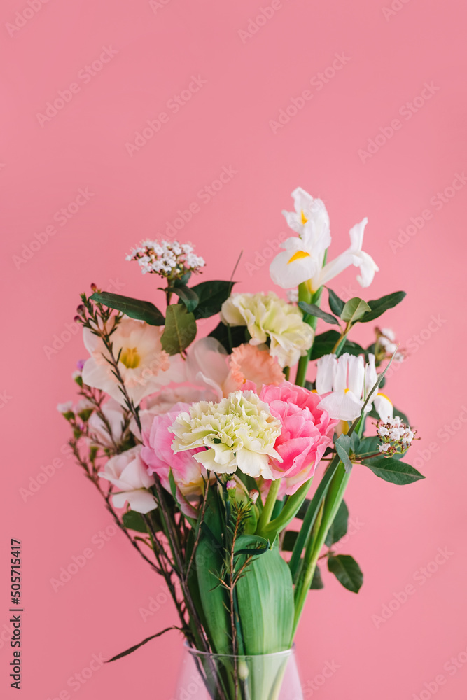 beautiful bouquet of carnations, daffodils, spray roses, Chamelacium hookata and white irises on pink background, copy space