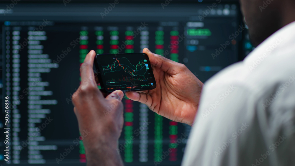 Cropped shot of male stock market broker analyzing graphs on smartphone Cropped shot of male stock market broker analyzing graphs on smartphone