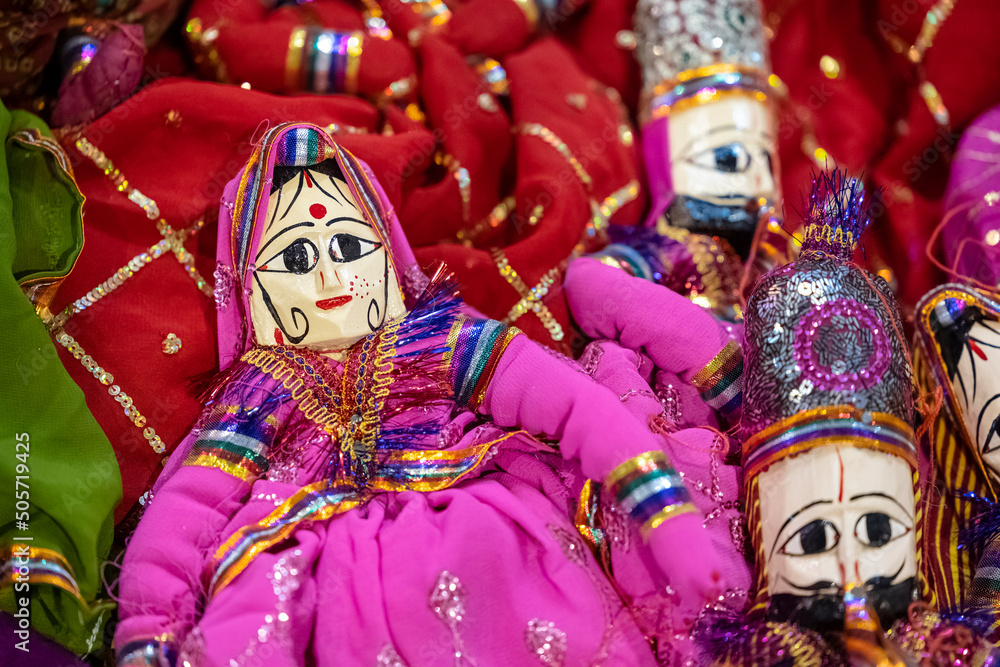 Handmade colorful rajasthani puppets hanging on blue colour wall for décor. Selective focus on puppet.