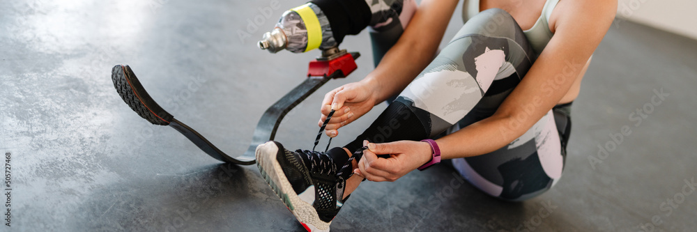 Young sportswoman with prosthesis tying her shoelaces