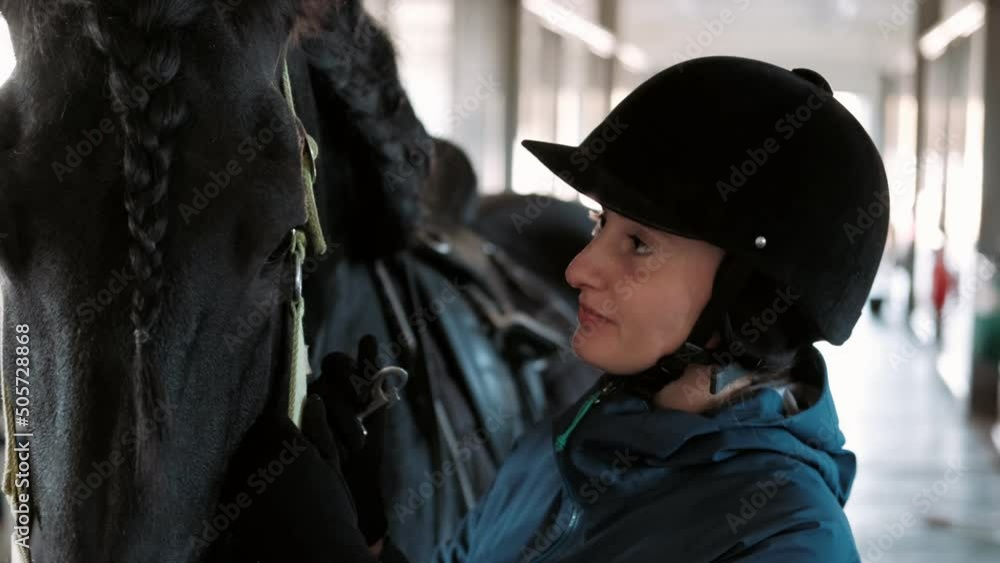 Girl makes preparation for horse riding, putting a bridle on horse. Cute cheerful girl looks at the horse. Equitation, jockeyship, equestrianism. Girl makes preparation for horse riding, putting a bridle on horse. Cute cheerful girl looks at the horse. Equitation, jockeyship, equestrianism.