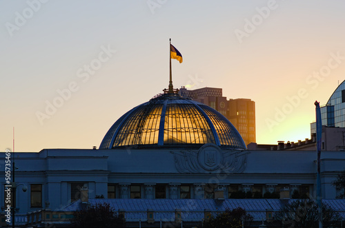 Ukrainian flag waving over Parliament (Verkhovna Rada of Ukraine) in Kyiv, Ukraine. Blue sky background. Colorful autumn sunset photo