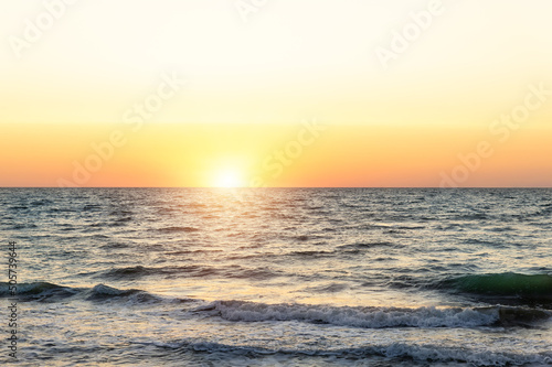 Scenic panoramic view of bright warm red orange dramatica sunrise or sunset at early morning over sand coast of ocean water surface. Beautiful seaside golden dusk panorama background on stormy sea