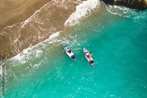 Top down aerial view of man and woman paddling on stand up paddle boards