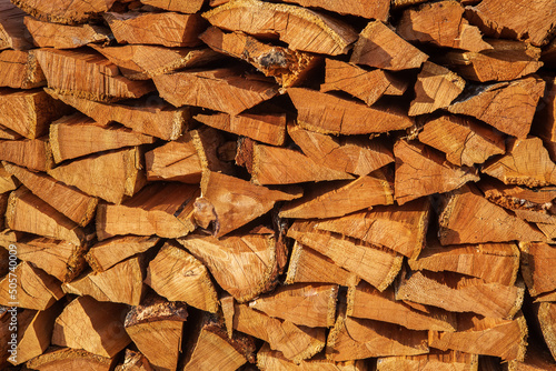 Natural texture of woodpile from coniferous trees. Pine firewood stacked on top of each other on a sunny day. Preparation of natural fuel.