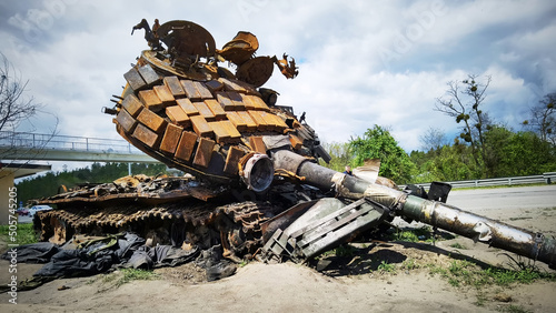 Kyiv region, Ukraine - May 15, 2022: War in Ukraine. Highway Kyiv - Zhytomyr. People take selfies against destroyed russian tank after russian atack in Febrary. photo