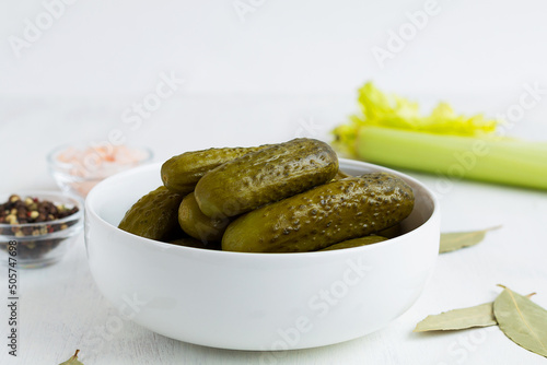 Pickled green cucumbers in a white bowl with salt and peppers and Ingredients. crunchy Marinated cucumbers gherkins. Salted Cucumbers on a white background. Canned vegetables. copy space