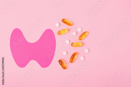 Top view of paper thyroid gland with gelatin capsules and tablets.World thyroid day concept. photo
