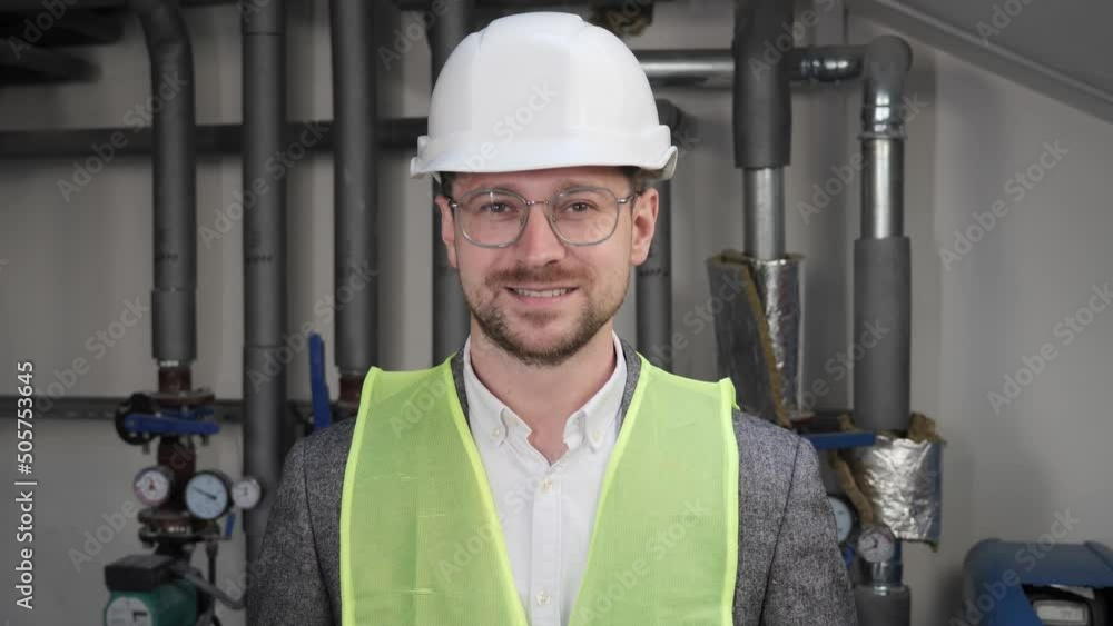 Close up face of smiling talented male architect in eyeglasses standing near water supply systems. Busy concentrated adult man engineer looking at camera positive. Professional Engineering. Close up face of smiling talented male architect in eyeglasses standing near water supply systems. Busy concentrated adult man engineer looking at camera positive. Professional Engineering.