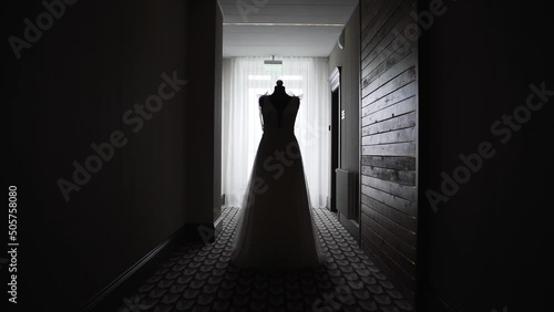 Wedding dress of the bride on the manik stands in the corridor of the hotel in silhouette photo