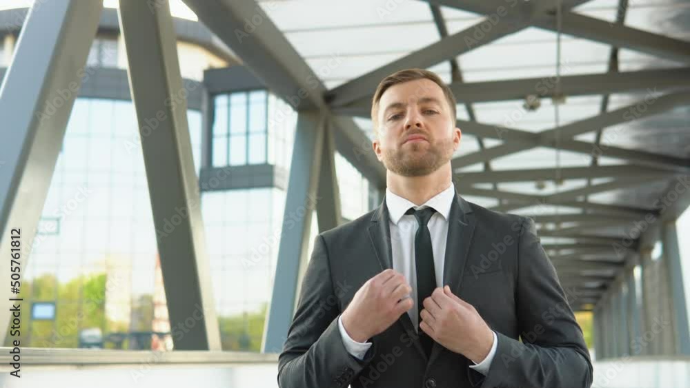 Businessman in suit walking near the business center, adjusting suit and tie Businessman in suit walking near the business center, adjusting suit and tie