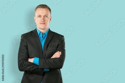 Smiling young businessman in black suit on pastel background