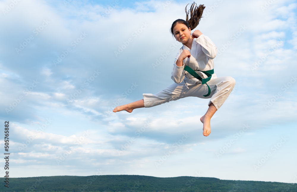 karate girl in kimono jump on sky background karate girl in kimono jump on sky background