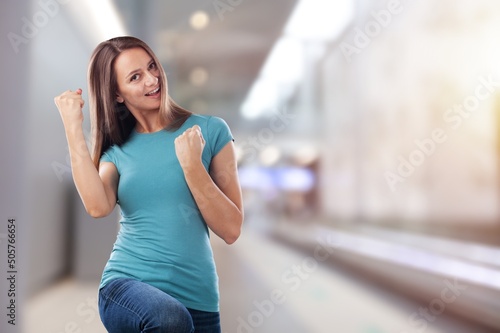 Cheerful beautiful woman with fists clenched celebrating victory expressing success on background.