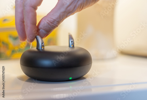 hearing aid held with two fingers while placing to charge