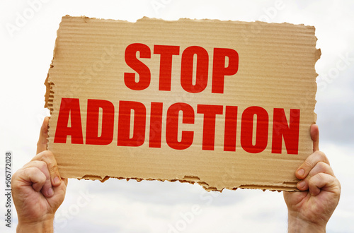 In the hands of a man is a cardboard sign with the inscription - Stop Addiction photo