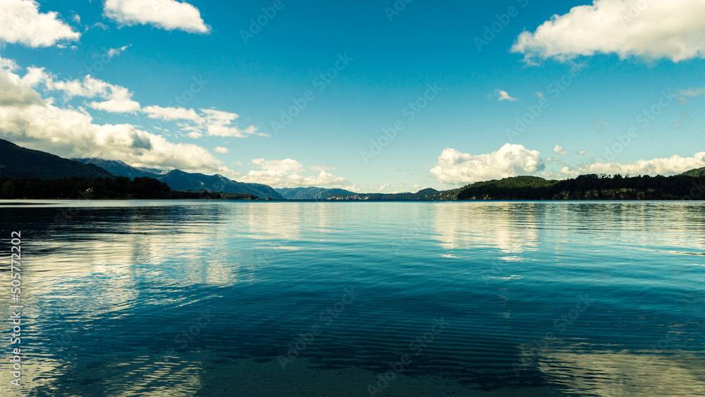 Blue lake reflecting the sky with mountain range in the background Blue lake reflecting the sky with mountain range in the background