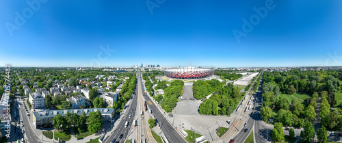 Zatłoczone rondo Waszyngtona w Warszawie w słoneczny dzień z lotu ptaka z drona, w tle stadion narodowy, dużo zieleni, wiosna