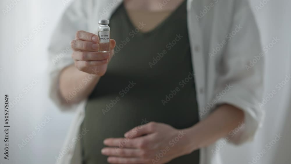 Covid-19 vaccine in hand of unrecognizable blurred pregnant woman standing indoors. Young Caucasian expectant advertising coronavirus vaccination. Pandemic and pregnancy concept Covid-19 vaccine in hand of unrecognizable blurred pregnant woman standing indoors. Young Caucasian expectant advertising coronavirus vaccination. Pandemic and pregnancy concept