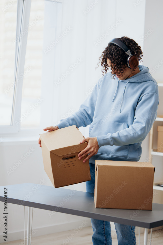 guy with curly hair unpacking things from boxes in the room interior guy with curly hair unpacking things from boxes in the room interior