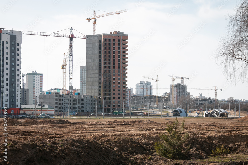 Construction cranes and new high-rise buildings on the site of an abandoned wasteland. The concept of building a new microdistrict. Construction cranes and new high-rise buildings on the site of an abandoned wasteland. The concept of building a new microdistrict.