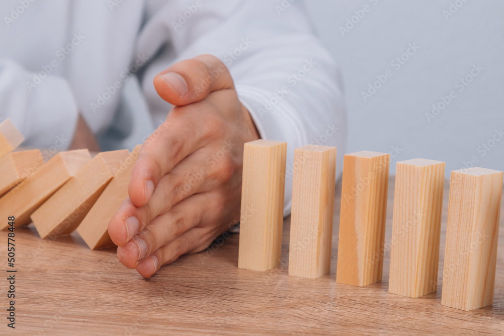 hand stops falling dominoes or wooden puzzle hand stops falling dominoes or wooden puzzle