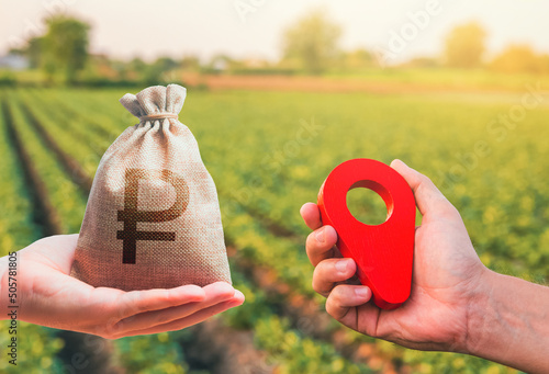 Hands with location pin and russian ruble money bag. Estimation cost of plots. Agriculture agribusiness. Transport and construction industry. Buying and selling land. Land market.