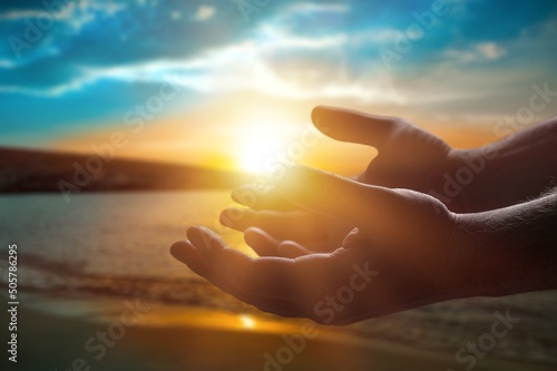 Silhouette human hands open palm up on sunset beach. Christian praying concept