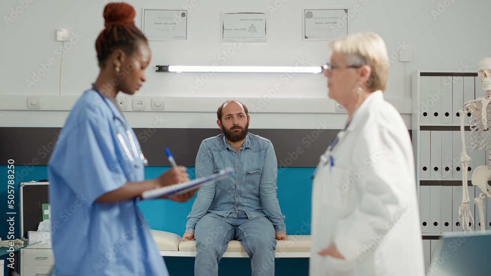 Obraz premium Young patient sitting in medical cabinet and waiting for exam results to find about disease diagnosis. Sick person attending consultation appointment with medical staff team in office.