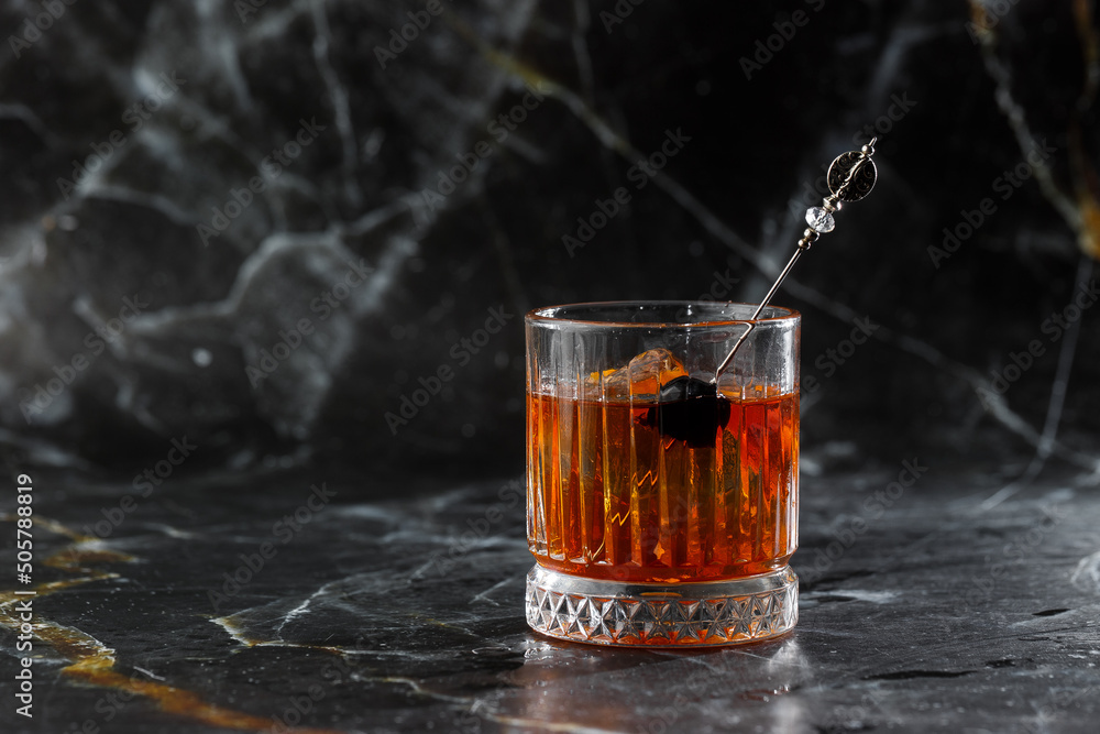 Old fashioned cocktail, consisting of Bourbon, Angostura Bitter, sugar cubes, a few drops of water, ice cubes, orange, maraschino cherry